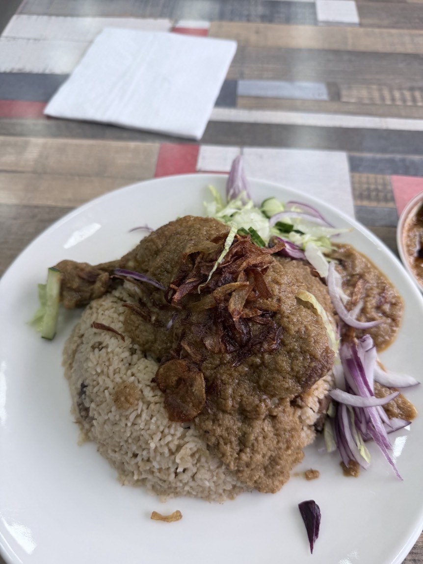 A plate of slow-cooked beef with pilau rice, fried onions and fresh salad at Lobongo.