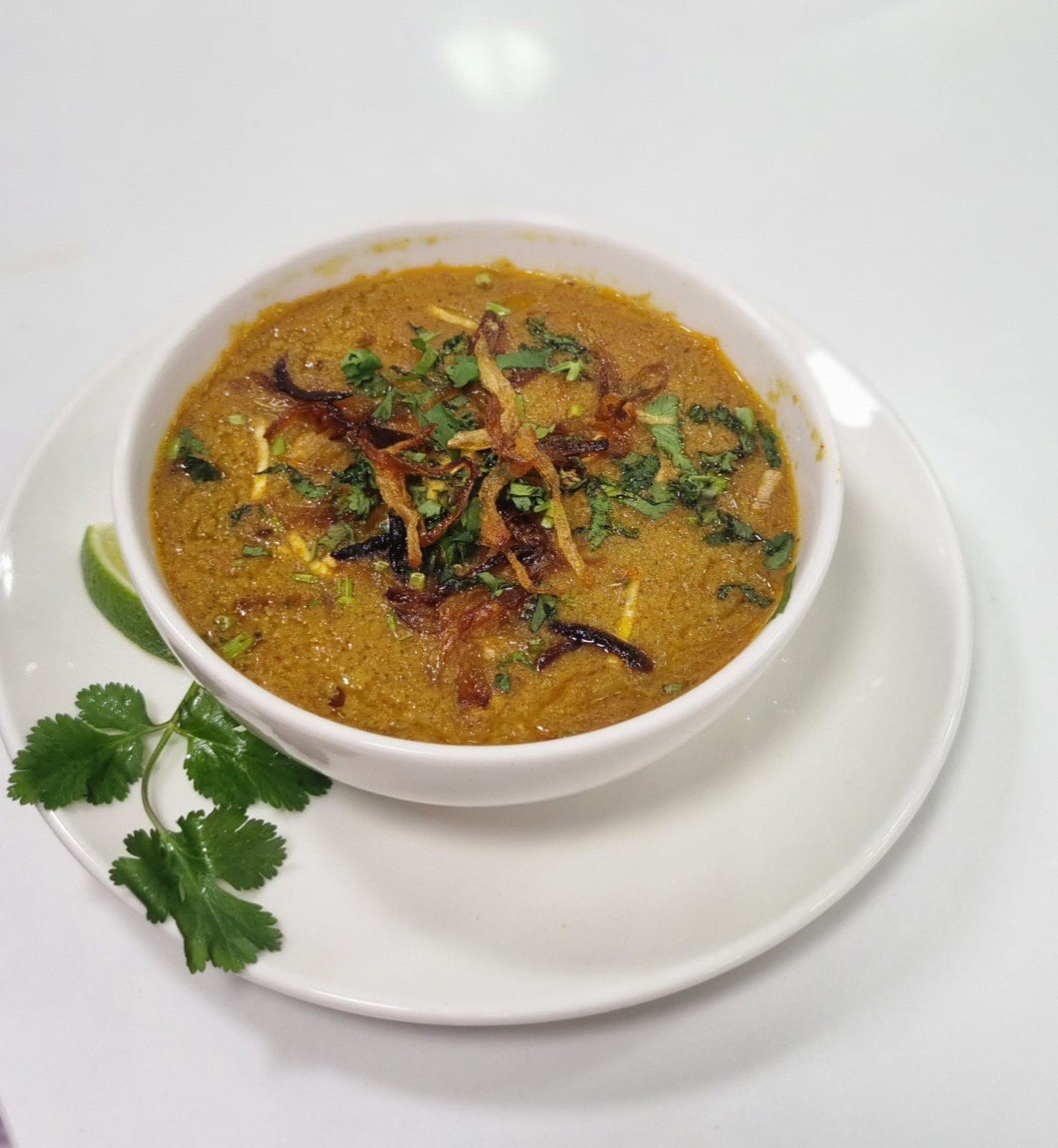 A bowl of haleem at Lobongo, a thick spiced lentil and meat porridge topped with fried onion, coriander and ginger.
