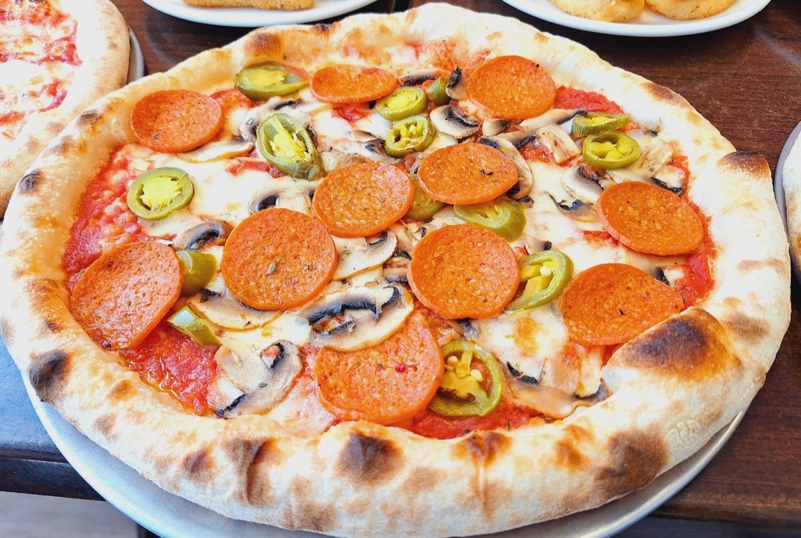 A wood-oven pizza at Lobongo with pepperoni, mushroom and jalapeño on a puffed, charred crust.